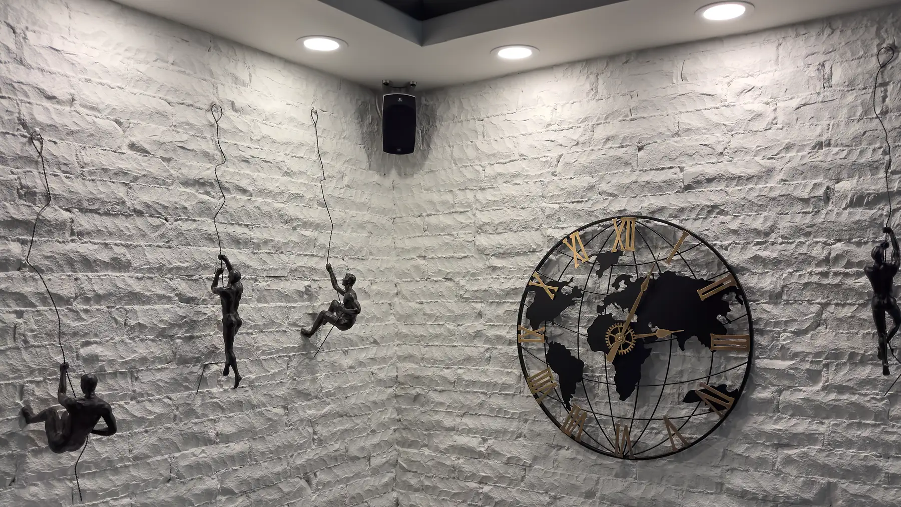 Mur de briques blanches du bureau, avec de petites figurines qui grimpent et une horloge